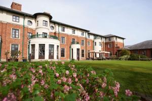 格洛斯特的住宿－Hilton Puckrup Hall Hotel & Golf Club, Tewkesbury，前面有粉红色花的砖砌大建筑