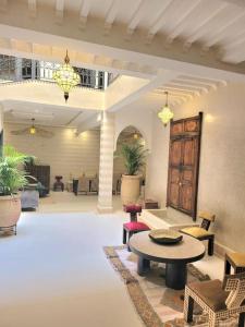 Riad Isahiac avec piscine en exclusivité في مراكش: غرفة معيشة مع طاولة وكراسي