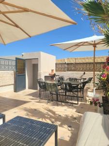 patio ze stołem, krzesłami i parasolami w obiekcie Riad Isahiac avec piscine en exclusivité w Marakeszu