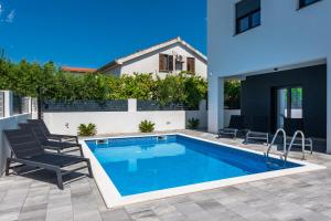 a swimming pool in a backyard with chairs and a house at House with pool Villa Angelo Vrsi in Vrsi