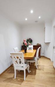 a dining room table with white chairs and flowers on it at Holiday Apartment in Abbey Wood