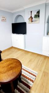 a living room with a table and a television at Holiday Apartment in Abbey Wood