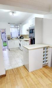 a white kitchen with white appliances and wooden floors at Holiday Apartment in Abbey Wood