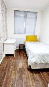 a bedroom with a bed and a desk and a window at Holiday Apartment in Abbey Wood