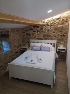 een slaapkamer met een wit bed in een kamer met stenen muren bij O Muiño do Torneiro in Pobra do Caramiñal