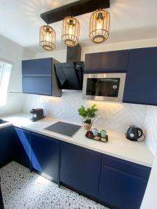 a kitchen with blue cabinets and a sink and lights at Splendide Studio avec balcon - Trouville centre in Trouville-sur-Mer