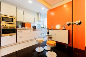 an orange and white kitchen with a glass table and stools at Frente al parque, en el centro in Bilbao