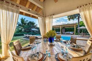 comedor con mesa, sillas y piscina en Sunny Vacation Villa No 68, en San Rafael del Yuma