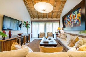 ein Wohnzimmer mit einem Sofa und einem TV in der Unterkunft Sunny Vacation Villa No 68 in San Rafael del Yuma