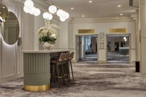 a lobby with a bar with chairs and a vase of flowers at Hilton Glasgow in Glasgow