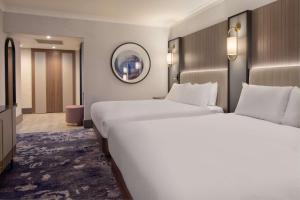 a hotel room with two beds and a mirror at Hilton Glasgow in Glasgow