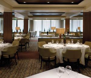 uma sala de jantar com mesas e cadeiras brancas em Hilton London Syon Park em Brentford