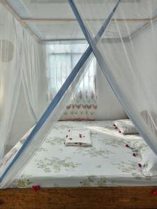 a bed with a canopy in a room with flowers at Kacho House in Jambiani