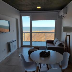 Una sala de estar con una mesa y una gran ventana. en MyA, en Monte Hermoso