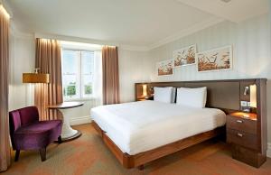 a bedroom with a large bed and a purple chair at Hilton London Hyde Park in London