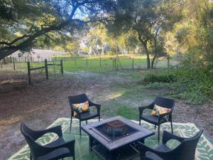 three chairs and a table in a field with trees at Your Personal 'Glamp' Site! AC - BBQ - Fast WiFi in DeLand