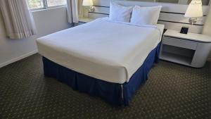 Cama grande en habitación de hotel con colcha blanca en Club Lakeridge, en Reno