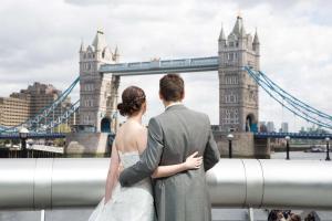 una novia y un novio parados frente al puente de la torre en Hilton London Tower Bridge en Londres