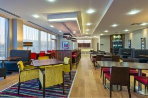 a dining room with tables and chairs and windows at Hampton by Hilton Luton Airport in Luton