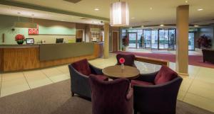 - un hall avec des chaises, une table et un comptoir dans l'établissement Hilton Garden Inn Luton North, à Luton