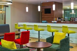 una sala de espera con sillas coloridas y un bar en Hampton by Hilton Luton Airport en Luton