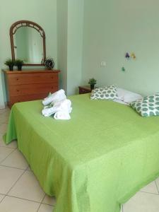 a bedroom with a green bed with towels on it at Villino Ulivo in Le Casette