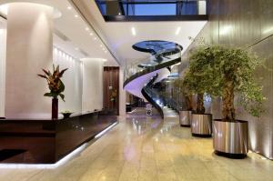a lobby with a spiral staircase and potted plants at Hilton Manchester Deansgate in Manchester