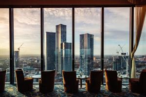 a restaurant with tables and chairs and a view of the city at Hilton Manchester Deansgate in Manchester
