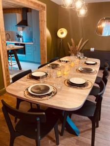 una mesa de madera con platos y copas de vino. en Maison Les Planches, en Gérardmer