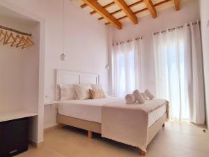 a white bedroom with a large bed with white pillows at Waki Conscious Hotel in Ciutadella