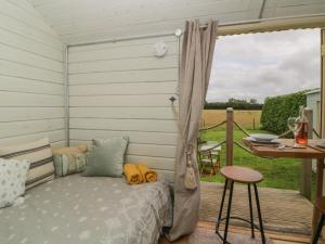 a room with a bed and a table on a deck at Flora's Hut in Liskeard