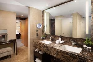 un bagno con due lavandini e un grande specchio di Conrad London St James a Londra