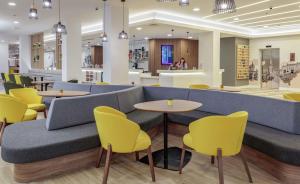 a waiting room with yellow chairs and a blue couch at Hampton By Hilton Edinburgh Airport in Ingliston