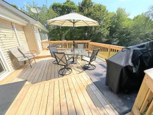 a wooden deck with a table and an umbrella at WOW!! Ultimate Pocono Retreat, Hot Tub, Game Room, Deck, Lakes, Skiing, Pools in Long Pond