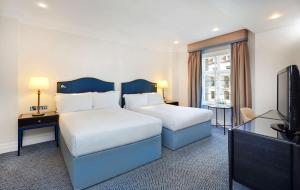 een hotelkamer met 2 bedden en een flatscreen-tv bij The Waldorf Hilton in Londen