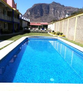 a blue swimming pool with a mountain in the background at Bungalows Boutique Tonantzin in Morelos