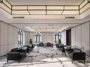 a lobby with black chairs and tables and windows at Hilton Beijing Daxing in Beijing