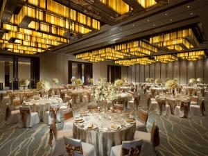 une grande salle de banquet avec des tables et des chaises blanches dans l'établissement Conrad Beijing by Hilton, à Pékin