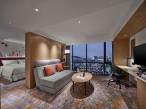 広州市にあるHilton Garden Inn Guangzhou Tianheのソファとベッドのあるホテルの部屋