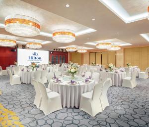 un salón de banquetes con mesas blancas y sillas blancas en Hilton Guangzhou Science City, Free Shuttle Bus to Canton Fair en Cantón