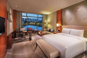 a bedroom with a large white bed and a living room at DoubleTree by Hilton Hotel Guangzhou-Science City-Free Shuttle Bus to Canton Fair Complex and Dining Offer in Guangzhou