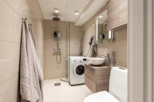 uma casa de banho com uma máquina de lavar roupa e um lavatório em Seaside Deluxe Loft - Beach, Free Parking & 10 min to Metro em Espoo