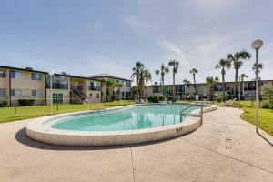 a large swimming pool with palm trees and a building at Sunny Florida Condo 4 Mi to Gulf Islands Seashore in Fort Walton Beach