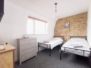 a bedroom with two beds and a brick wall at Entire 3 bedroom house 5 minutes from the beach in Kent