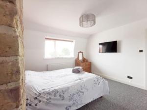 a white bedroom with a bed and a television at Entire 3 bedroom house 5 minutes from the beach in Kent