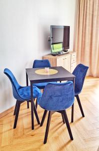 a dining room table with blue chairs and a television at Blue Amber in Rumia