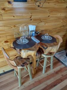 a wooden table with two chairs and wine glasses at HOSPEDAGEM CK in Urubici