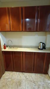 a kitchen with wooden cabinets and a tea kettle on a counter at Luluat Al sharq Al Awsat in Makkah