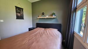 a bedroom with a bed with a pink blanket on it at Huisje Weideblik in Doornspijk