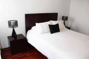 1 dormitorio con 1 cama blanca y 2 lámparas en DEPARTAMENTO con VISTA AL MAR, en Lima